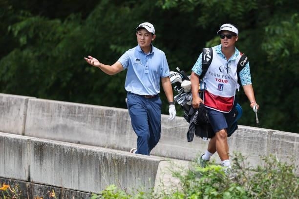 Dylan Wu talks with his caddie as he walks across a bridge to the 8th green during the final round of the Price Cutter Charity Championship presented...