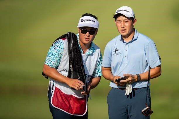 Dylan Wu looks on with his caddie and younger brother Jeremy Wu on the 18th green during the final round of the Price Cutter Charity Championship...