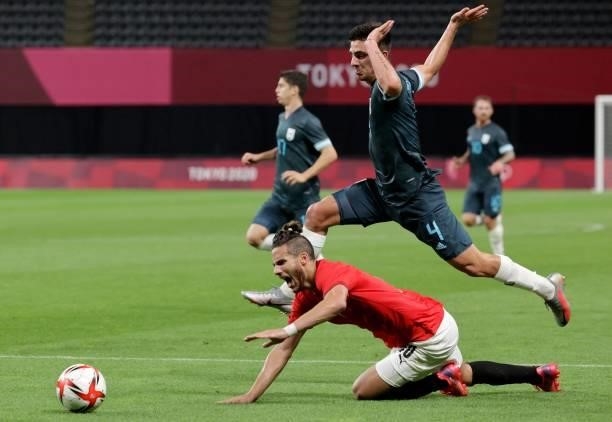 Egypt's forward Ramadan Sobhi falls on the pitch while Argentina's defender Hernan De La Fuente jumps behind him during the Tokyo 2020 Olympic Games...
