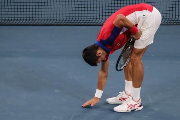 Serbia's Novak Djokovic touches the ground as celebrates after defeating Germany's Jan-Lennard Struff during their Tokyo 2020 Olympic Games men's...