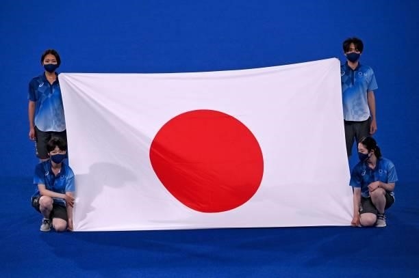 Volunteers display the national flag of Japan before the women's pool B match of the Tokyo 2020 Olympic Games field hockey competition between Japan...