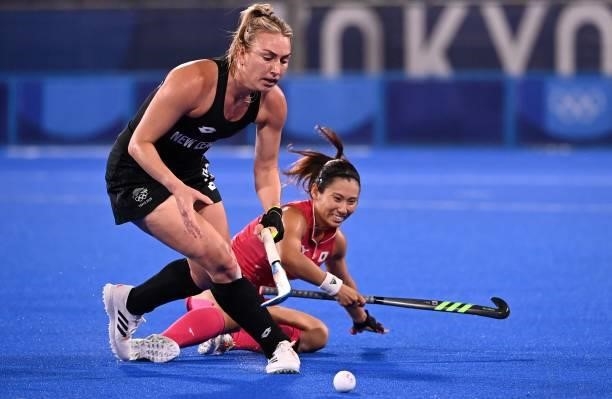 New Zealand's Liz Thompson carries the ball past Japan's Yuri Nagai during their women's pool B match of the Tokyo 2020 Olympic Games field hockey...