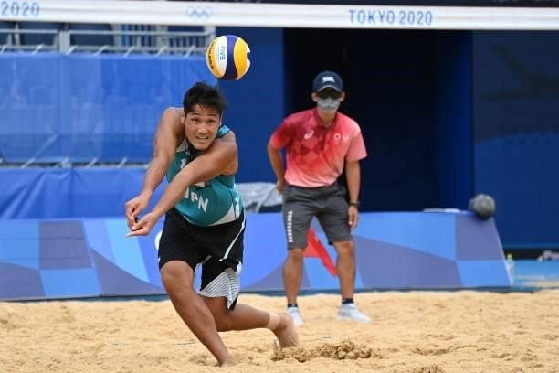 Japan's Yusuke Ishijima reaches for the ball in their men's preliminary beach volleyball pool F match between Japan and Italy during the Tokyo 2020...