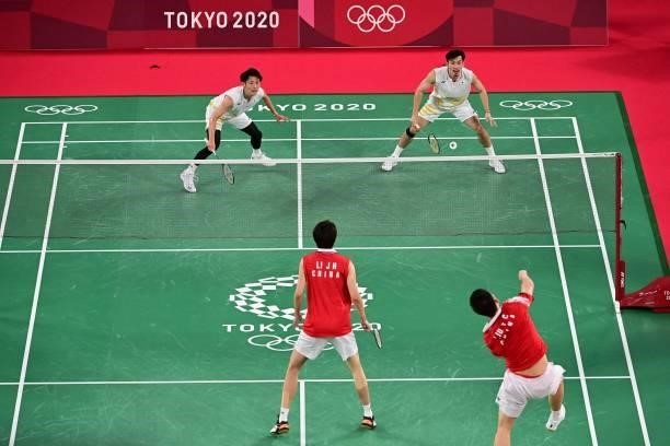 China's Liu Yuchen hits a shot next to China's Li Junhui in their men's doubles badminton group stage match against Japan's Keigo Sonoda and Japan's...