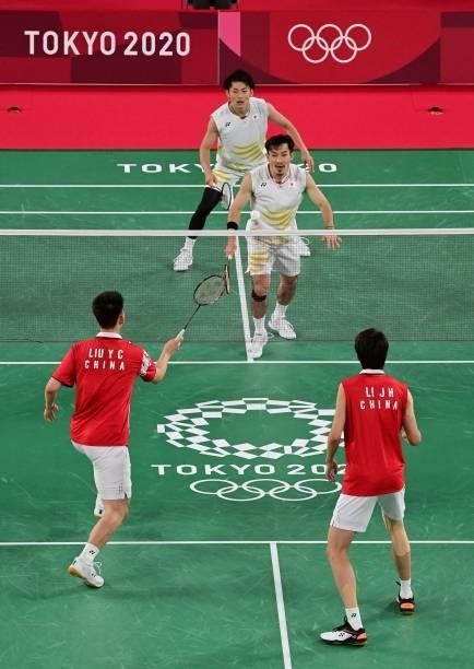 China's Liu Yuchen hits a shot next to China's Li Junhui in their men's doubles badminton group stage match against Japan's Keigo Sonoda and Japan's...