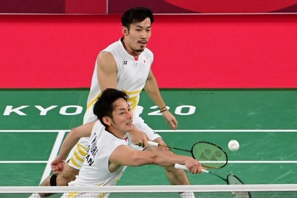 Japan's Takeshi Kamura hits a shot next to Japan's Keigo Sonoda in their men's doubles badminton group stage match against China's Liu Yuchen and...