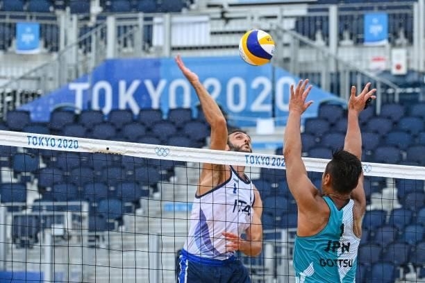 Italy's Paolo Nicolai attempts a shot past Japan's Yusuke Ishijima in their men's preliminary beach volleyball pool F match between Japan and Italy...