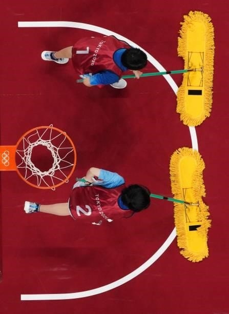 Volunteers clean the court during the women's preliminary round group B basketball match between France and Japan during the Tokyo 2020 Olympic Games...