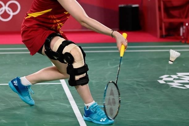 Japan's Sayaka Hirota, wearing a leg brace, hits a shot next to Japan's Yuki Fukushima in their women's doubles badminton group stage match against...