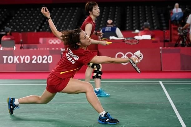 Japan's Yuki Fukushima hits a shot next to Japan's Sayaka Hirota in their women's doubles badminton group stage match against Indonesia's Greysia...