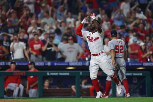 Andrew McCutchen of the Philadelphia Phillies celebrates after he rounds third base while closer Brad Hand of the Washington Nationals walks off the...