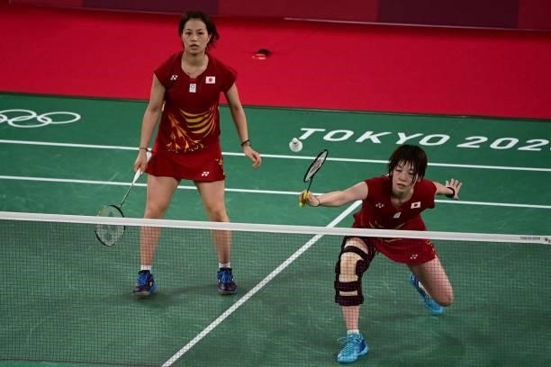 Japan's Sayaka Hirota , wearing a leg brace, hits a shot next to Japan's Yuki Fukushima in their women's doubles badminton group stage match against...