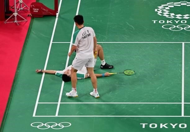 Taiwan's Wang Chi-lin lays on the floor as Taiwan's Lee Yang stands over him in their men's doubles badminton group stage match against Indonesia's...
