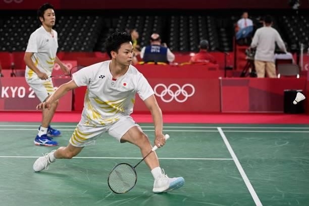 Japan's Yuta Watanabe hits a shot next to Japan's Hiroyuki Endo in their men's doubles badminton group stage match against Denmark's Kim Astrup and...