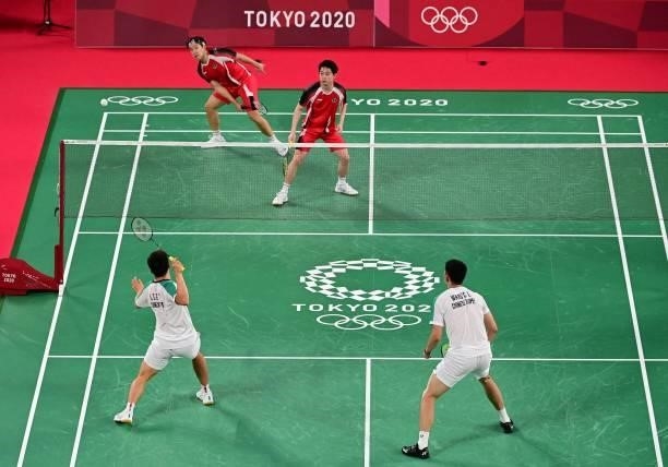 Taiwan's Lee Yang hits a shot next to Taiwan's Wang Chi-lin in their men's doubles badminton group stage match against Indonesia's Marcus Fernaldi...