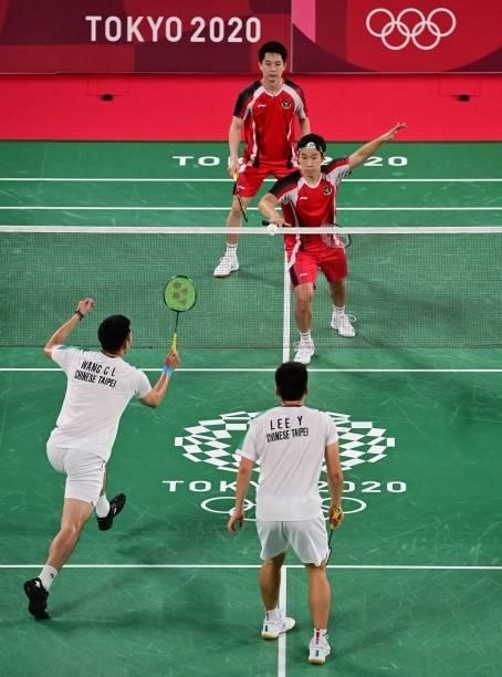Taiwan's Wang Chi-lin hits a shot next to Taiwan's Lee Yang in their men's doubles badminton group stage match against Indonesia's Marcus Fernaldi...