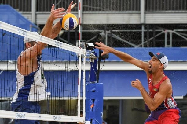 S Nicholas Lucena hits a shot as Brazil's Alison Cerutti blocks in their men's preliminary beach volleyball pool D match between Brazil and the USA...
