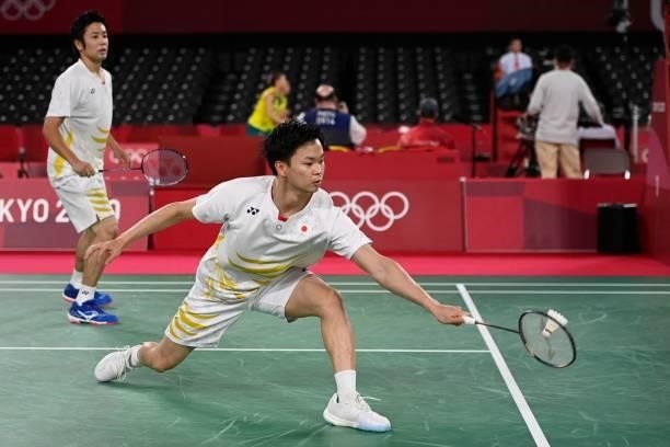 Japan's Yuta Watanabe hits a shot next to Japan's Hiroyuki Endo in their men's doubles badminton group stage match against Denmark's Kim Astrup and...