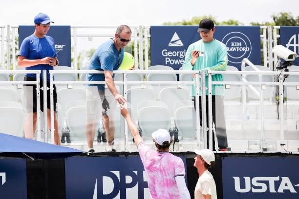 Reilly Opelka of the United States hands a marker back to a spectator after signing an autograph following a doubles match at the Truist Atlanta Open...