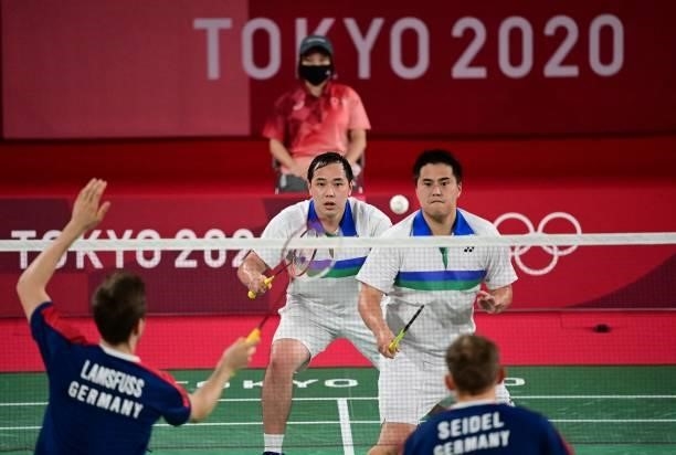 Germany's Mark Lamsfuss hits a shot next to Germany's Marvin Seidel in their men's doubles badminton group stage match against USA's Phillip Chew and...