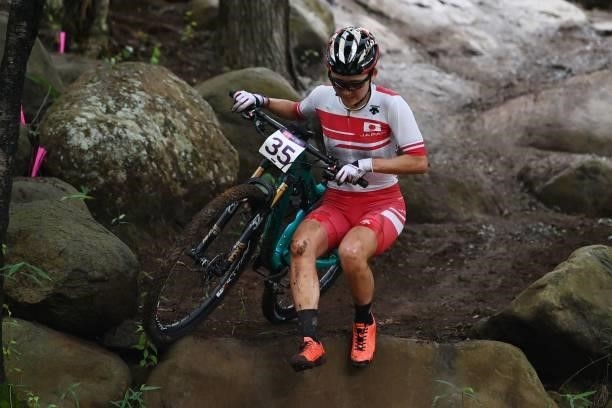 Japan's Miho Imai walks through a rocky section in the cycling mountain bike women's cross-country race during the Tokyo 2020 Olympic Games at the...
