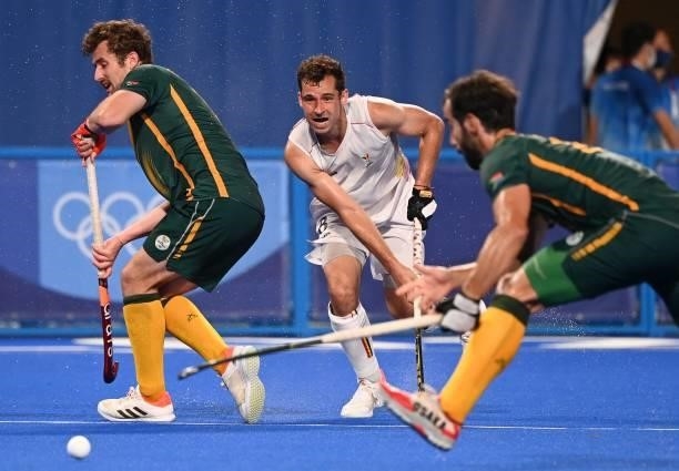 Belgium's Sebastien Dockier strikes the ball past South Africa's Matthew Guise-Brown and Daniel Bell during their men's pool B match of the Tokyo...