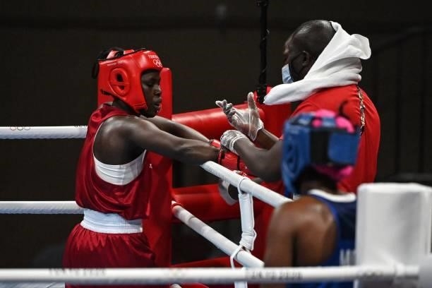 Kenya's Elizabeth Akinyi talks with her coach after losing by KO against Mozambique's Acinda Helena Panguana at the end of their women's welter...