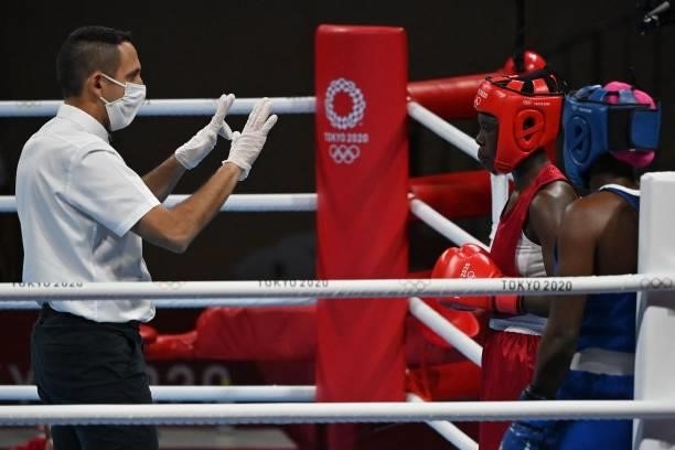 The referee gestures to Kenya's Elizabeth Akinyi after she lost by KO her fight against Mozambique's Acinda Helena Panguana during their women's...