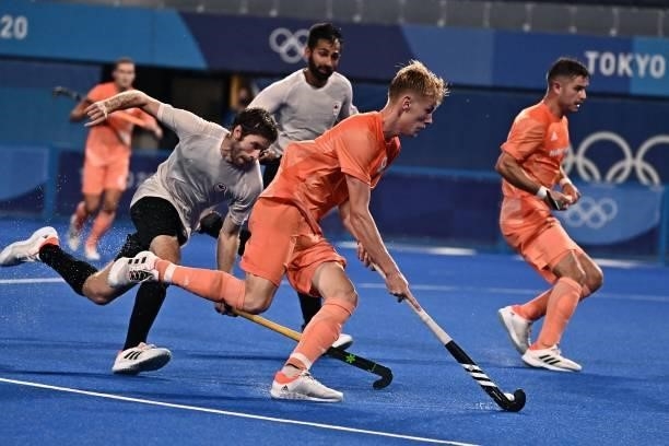 Netherlands' Joep Paul Eric De Mol drives the ball to score as he is marked by during their men's pool B match of the Tokyo 2020 Olympic Games field...
