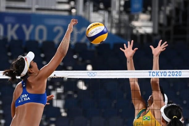 China's Wang Fan tries to block a shot by China's Xia Xinyi in their women's preliminary beach volleyball pool C match between Brazil and China...