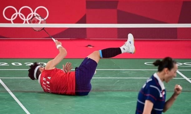 China's Li Yinhui falls on the court in her women's doubles badminton group stage match with China's Du Yue against South Korea's Lee So-hee and...
