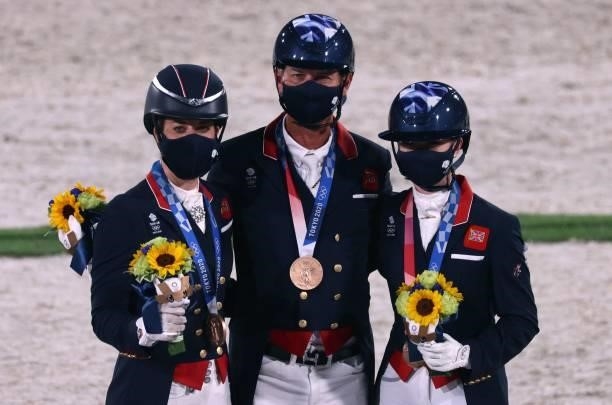Bronze medalists Britain's Charlotte Dujardin, Carl Hester and Charlotte Fry celebrate on the podium of the dressage grand prix special team...