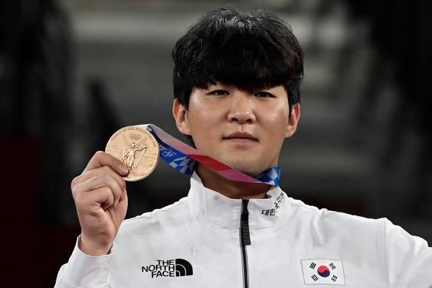Bronze medalist South Korea's In Kyo-don pose on the podium after the the taekwondo men's +80kg medal bouts during the Tokyo 2020 Olympic Games at...