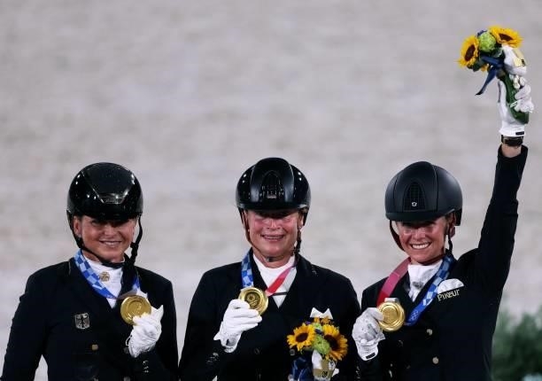 Gold medalist Germany's Dorothee Schneider, Isabell Werth and Jessica von Bredow-Werndl celebrate on the podium of the dressage grand prix special...