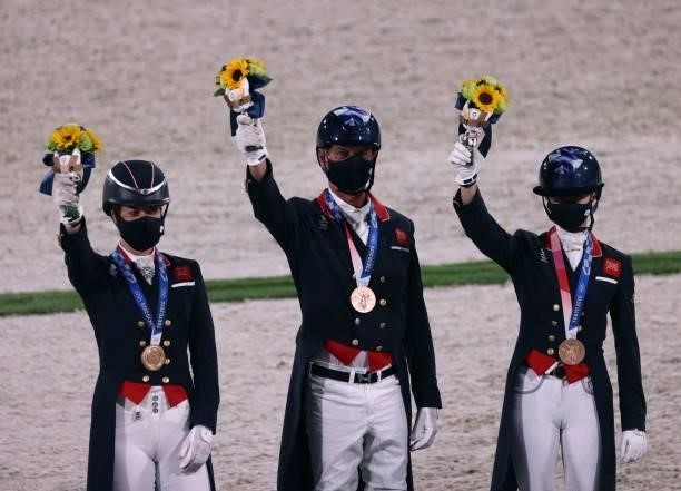 Bronze medalists Britain's Charlotte Dujardin, Carl Hester and Charlotte Fry celebrate on the podium of the dressage grand prix special team...