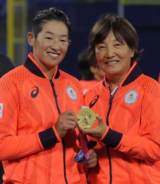 Japan's Yukiko Ueno and Japan's head coach Reika Utsugi pose while holding a gold medal together following the medal ceremony for the softball...