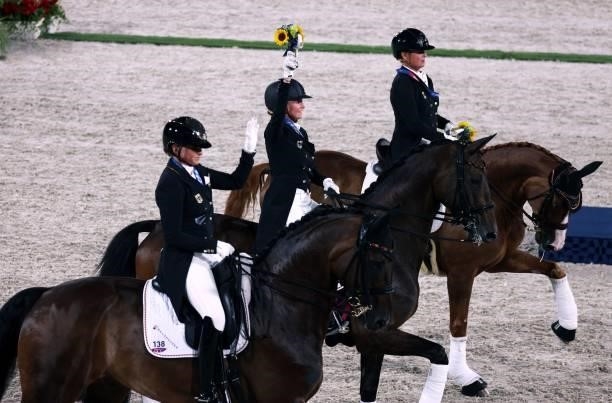 Gold medalist Germany's Dorothee Schneider, Jessica von Bredow-Werndl and Isabell Werth ride together after the medal ceremony of the dressage grand...