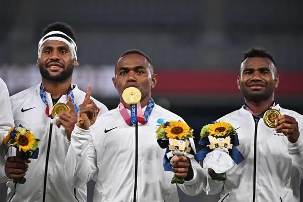 Fiji's players celebrate with their gold medals while standing on the podium for the victory ceremony after the men's final rugby sevens match during...