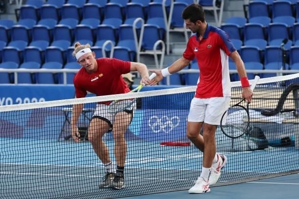 Serbia's Novak Djokovic helps Spain's Alejandro Davidovich Fokina to stand up after falling down during their Tokyo 2020 Olympic Games men's singles...