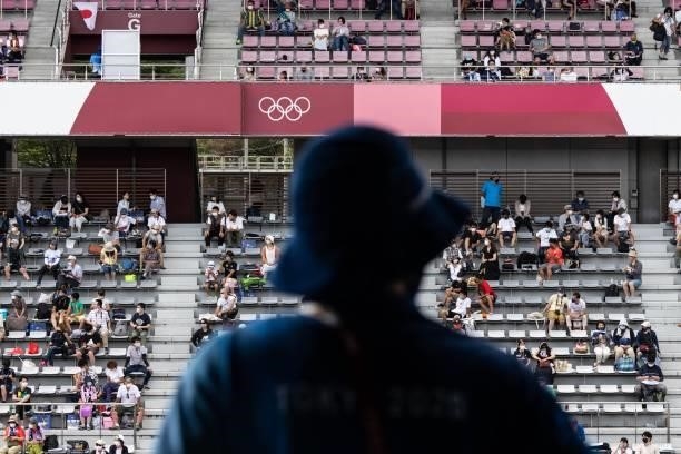 Staff member look at spectators watching the men's cycling road individual time trial during the Tokyo 2020 Olympic Games at the Fuji International...