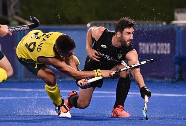 Australia's Tim Brand strikes the ball past New Zealand's Kane Russell to score during their men's pool A match of the Tokyo 2020 Olympic Games field...
