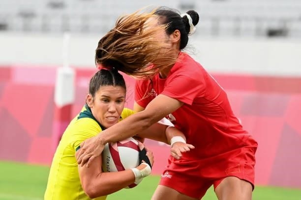 Australia's Charlotte Caslick is tackled by China's Yang Feifei in the women's pool C rugby sevens match between Australia and China during the Tokyo...