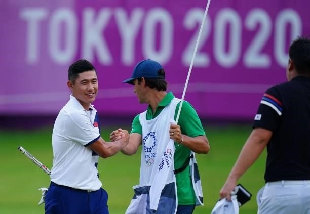S Collin Morikawa shakes hands with unidentified caddy as he holes out on the 18th green in round 1 of the mens golf individual stroke play during...