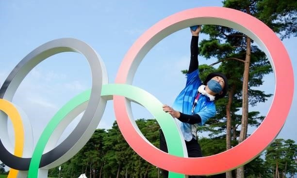 Volunteer wipes the Olympic symbol prior to start round 1 of the mens golf individual stroke play during the Tokyo 2020 Olympic Games at the...