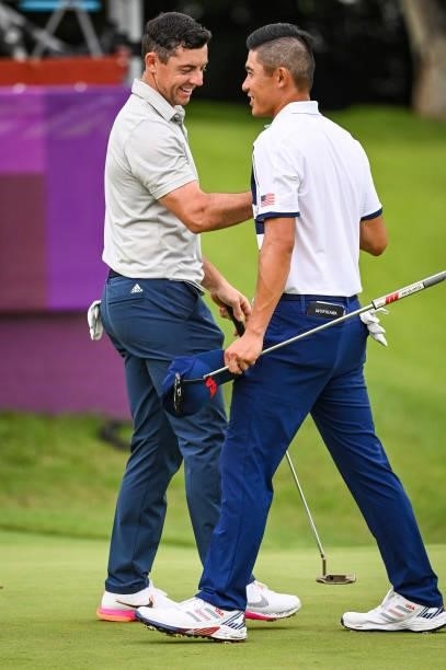 Rory McIlroy of Team Ireland smiles with Collin Morikawa of Team USA on the 18th hole following the first round of Mens Individual Stroke Play Golf...