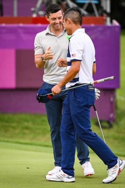 Rory McIlroy of Team Ireland smiles with Collin Morikawa of Team USA on the 18th hole following the first round of Mens Individual Stroke Play Golf...