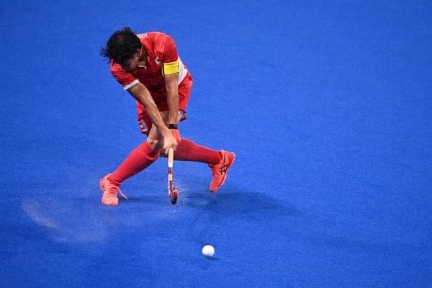 Japan's Manabu Yamashita strikes the ball during the men's pool A match of the Tokyo 2020 Olympic Games field hockey competition against India, at...