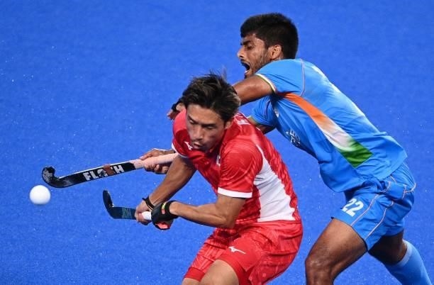 Japan's Kenta Tanaka and India's Varun Kumar vie for the ball during their men's pool A match of the Tokyo 2020 Olympic Games field hockey...