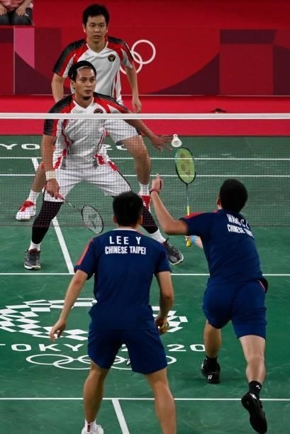 Taiwan's Wang Chi-lin hits a shot next to Taiwan's Lee Yang in their men's doubles badminton semi-final match against Indonesia's Mohammad Ahsan and...