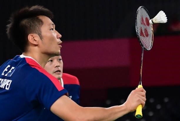 Taiwan's Lee Yang hits a shot next to Taiwan's Wang Chi-lin in their men's doubles badminton semi-final match against Indonesia's Mohammad Ahsan and...